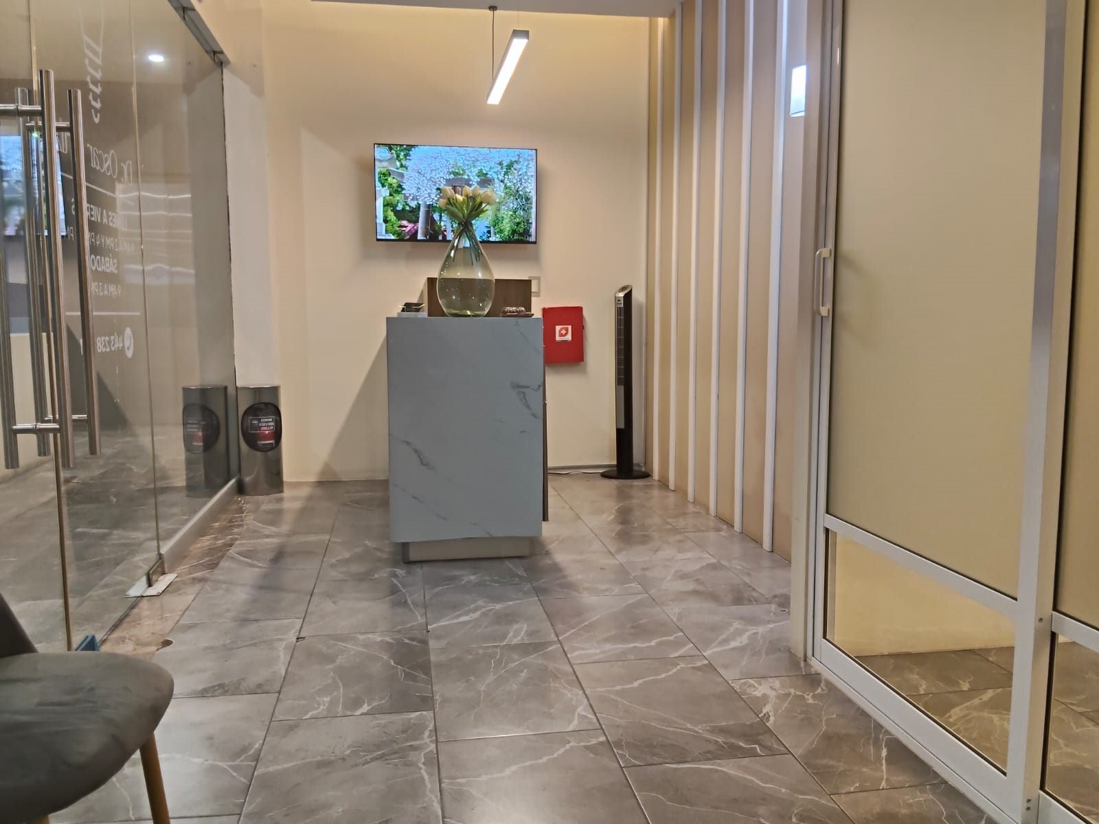 Recepción del consultorio de periodoncia e implantología en Plaza Sauce, Zamora, con mostrador de mármol y pantalla informativa